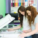 two female students using a printer photocopier