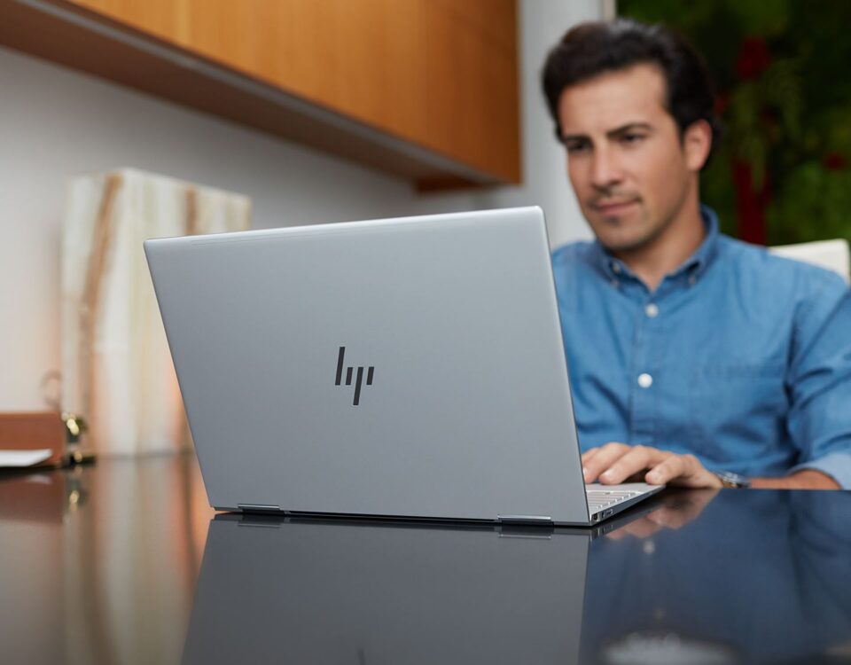 Man in blue shirt sitting in front of HP laptop in office