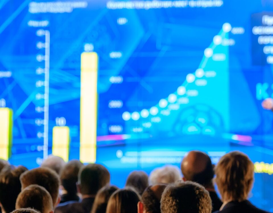 business conference presenter on stage showing graphs charts