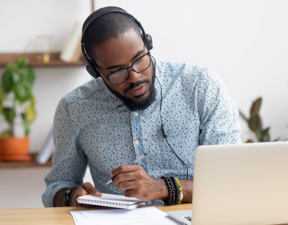 man wearing headphones while writing notes