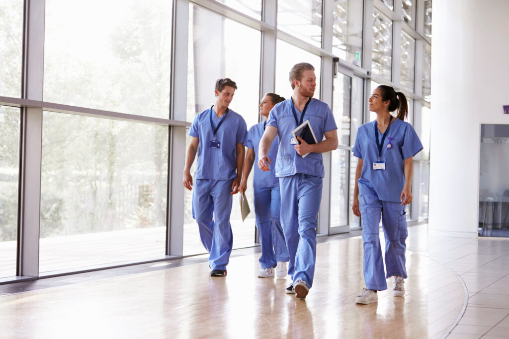 nhs healthcare workers walking in front of glass window hall