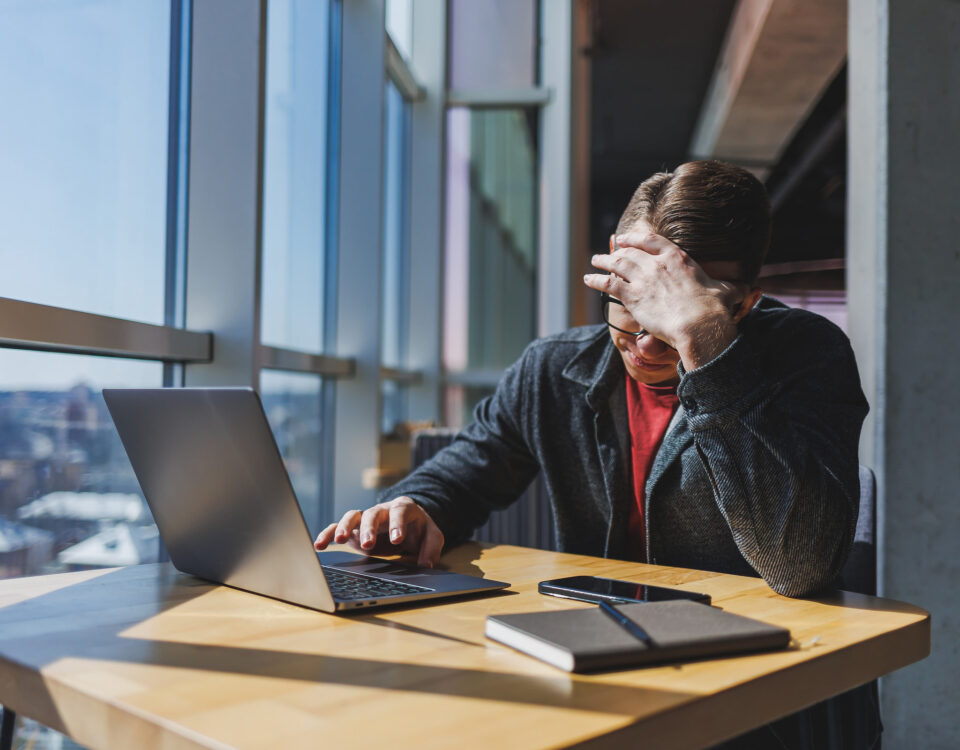 man looking stressed at laptop in office disconnect employee