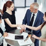 handshake-between four businesspeople around coffee table