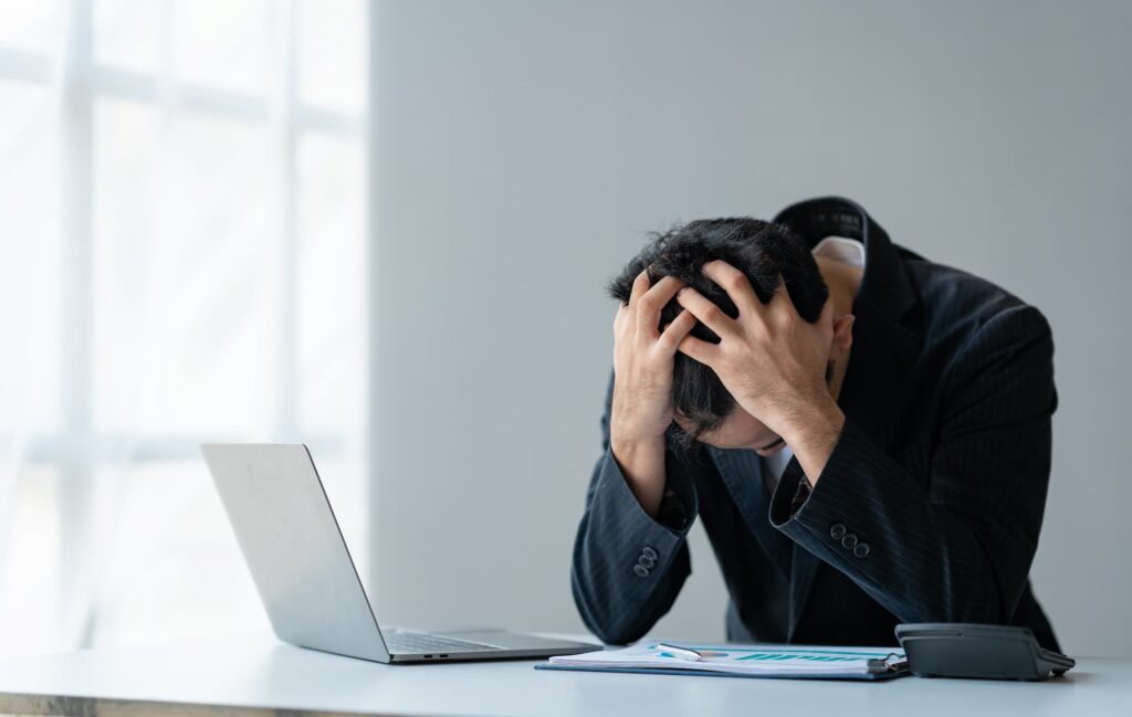 man at computer clutches his head in frustration