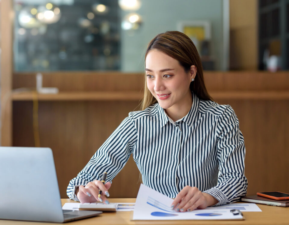 woman in striped shirt doing work laptop coffee cafe