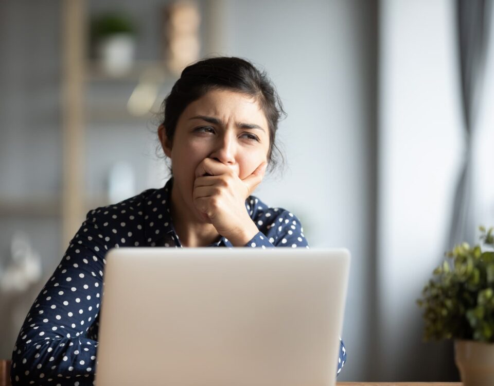 woman yawning at desk when hybrid working
