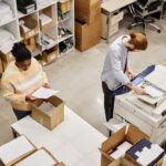 worker scanning while colleague packs boxes