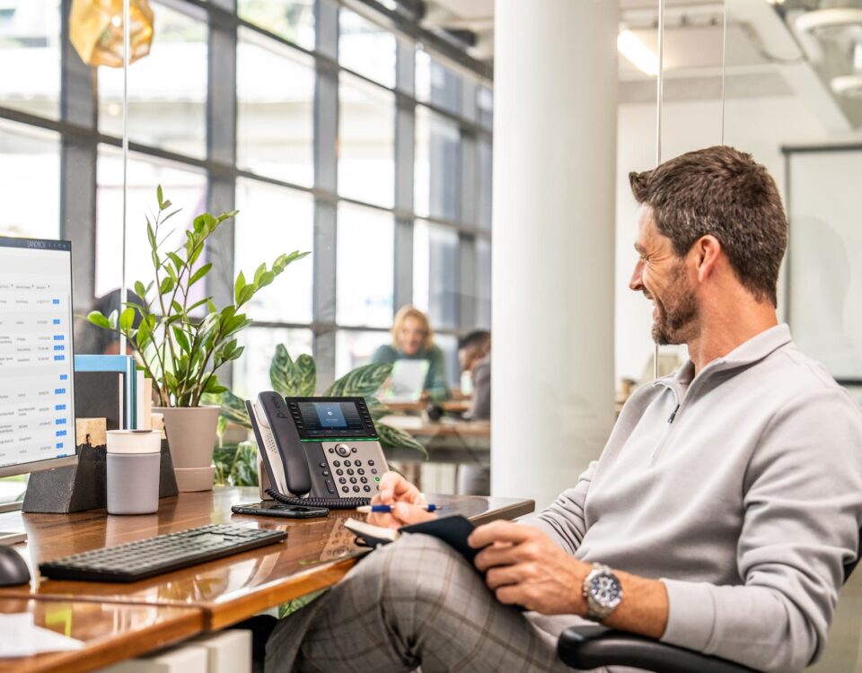 man at desktop using poly telecoms setup