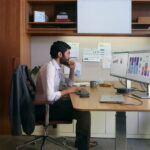 man sitting at finance desk HP monitor